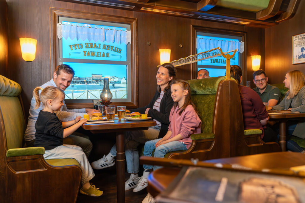 Familie sitzt an einem Tisch im Restaurant und genießt Essen und Getränke in einer gemütlichen Atmosphäre.